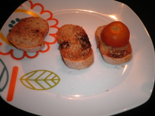 Wer Knoblauch mag, schneidet diese auf und reibt damit das Brot ein. Die Tomate wird halbiert und ebenfalls kräftig auf dem Weißbrot ausgedrückt und verrieben.