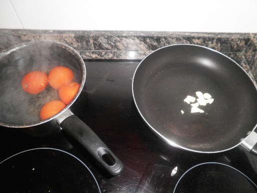 Erst die Tomaten überbrühen und die Haut abziehen, gleichzeitig etwas Knoblauch anrösten.
