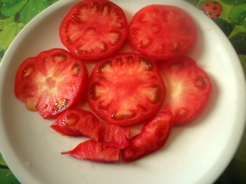 Tomaten in feine Scheiben schneiden und auf dem Teller zurecht legen.